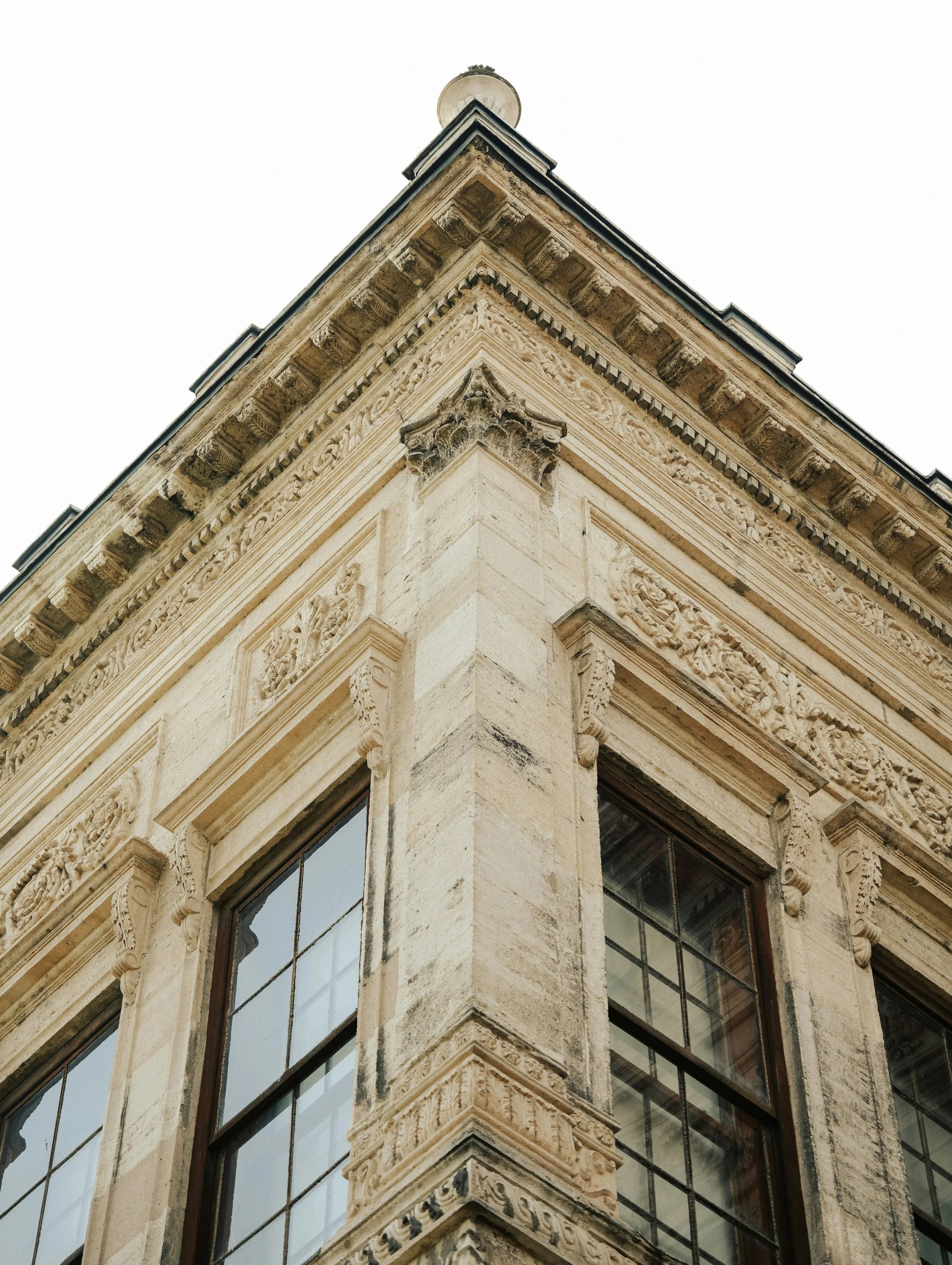 Close-up of the corner of a historic stone building with ornate architectural details and large windows.