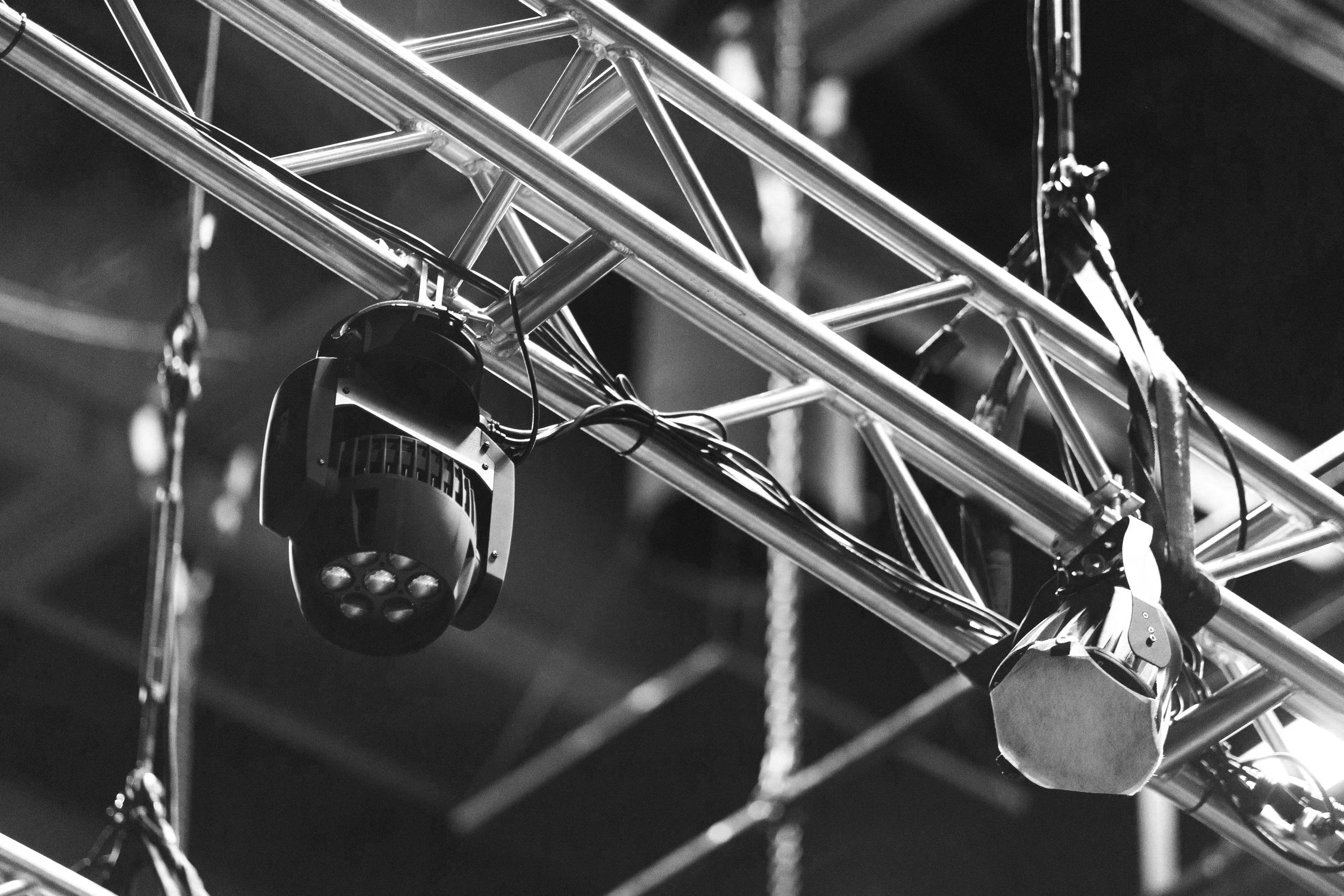 Stage lighting equipment hanging from a metal truss on a theater or concert stage.