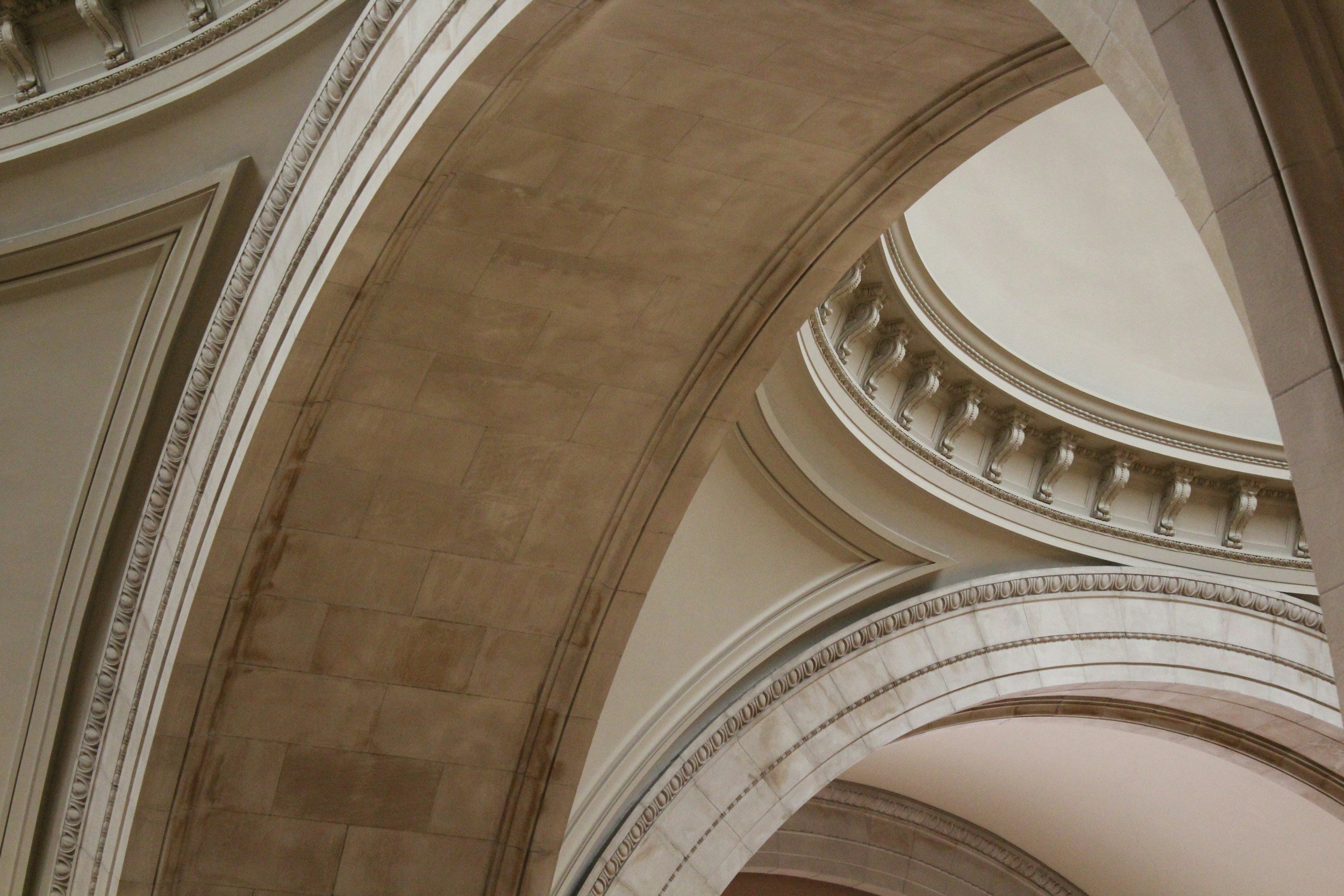 Archways and curved balcony with decorative molding in a classical building interior.